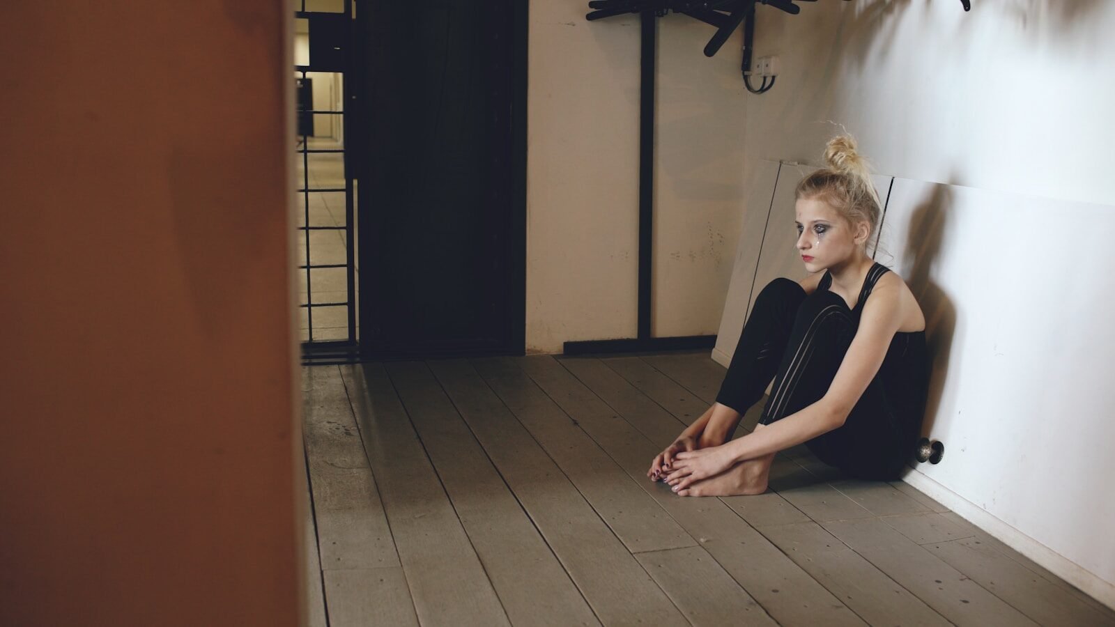 A young woman sits alone in a dimly lit room.